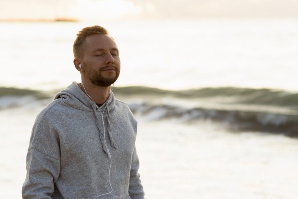 En person sidder trygt med lukkede øjne og lytter til en rolig lydsession mod angst